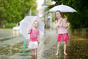 Two cute little sisters having fun under a rain