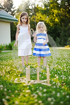 Two cute little sisters playing ring toss game outdoors