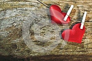 Two cute red hearts on string with clothes pegs on wooden background. Romantic Valentine`s Day scene with copy space.