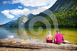 Two cute sisters enjoying the view of deep green waters of Konigssee, known as Germany`s deepest and cleanest lake, located in th