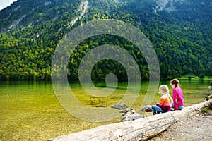 Two cute sisters enjoying the view of deep green waters of Konigssee, known as Germany`s deepest and cleanest lake, located in th