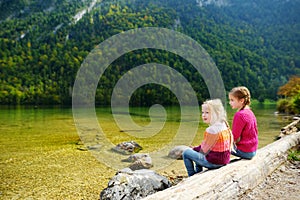 Two cute sisters enjoying the view of deep green waters of Konigssee, known as Germany`s deepest and cleanest lake, located in th