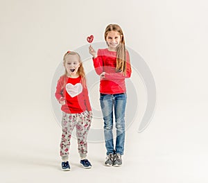 Two cute sisters with heart shaped lollipops