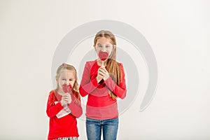 Two cute sisters with heart shaped lollipops