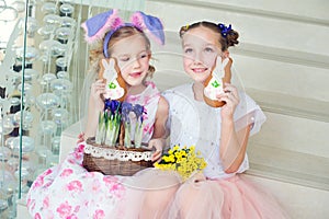 Two cute sisters sitting indoors with bunny ears, flowers and gi