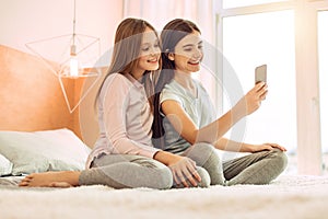 Two cute sisters taking selfies on bed