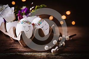 Two cute sleeping Eastereggs in a paper egg box on dark wooden background