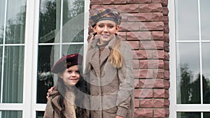 Two cute smiling girls in berets standing together outdoor