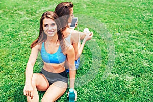 Two cute sporty girls relaxing after workout outdoor