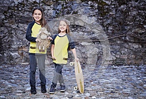 Two cute teenage females with skateboard and plushy toy.