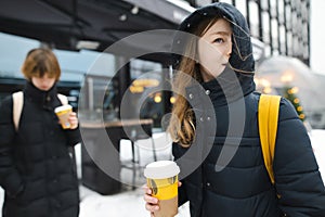 Two cute teenage girls with takeaway coffee cups on winter day. Teenager kids drinking hot beverage on chilly day