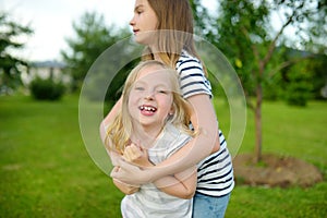 Two cute young sisters having fun together on beautiful summer day. Active family leisure with kids