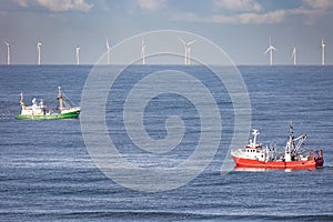 Two cutters passing each other with wind turbines of a windfarm in the background