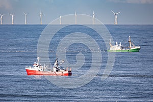 Two cutters passing each other with wind turbines of a windfarm in the background