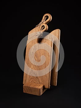 Figured cutting wooden boards on a stand, black background. Items for the kitchen.