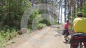 Two cyclists drive out of the forest to the seashore.