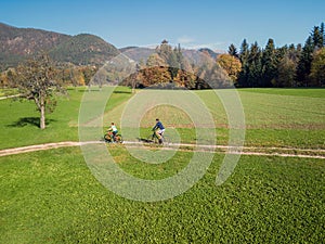 Two cyclists enjoying a ride along the road across pastures in an autumn