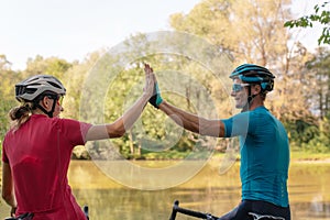 Two cyclists high-five each other on a river shoreline