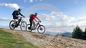 Two cyclists men riding electric bikes outdoors in the mountains.