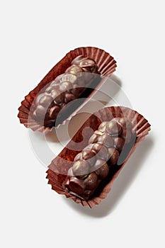 Two dark chocolate bars with hazelnuts in paper wrappers