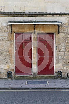 Two dark red front doors on the stone wall