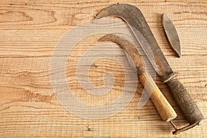 Two dated and used billhooks on wooden background