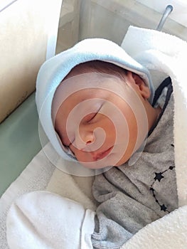 Two days old newborn baby boy, sleeping in hospital cot