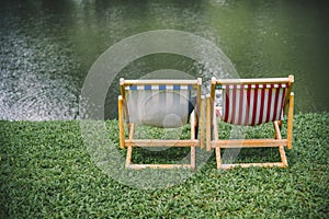 Two Deck chairs on lush green lawn with trees and in front of the river