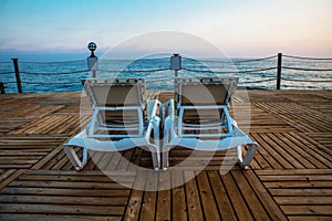 Two deck chairs at pier