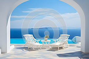 Two deck chairs on terrace with pool with stunning sea view. Traditional mediterranean white architecture with arch. Summer