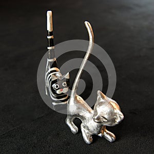 Two decorative cats of tin and wood  against a black background