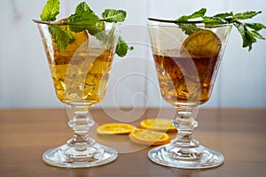 Two decorative glasses decorated with ice cubes, orange slice and mint sprig