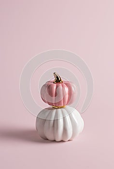 Two decorative glossy pumpkins standing vertically on top of each other on pink background