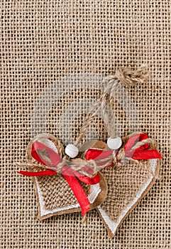 Two decorative hearts on burlap background.