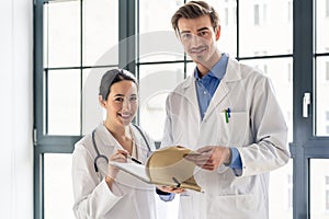 Two dedicated doctors smiling while holding a folder with medical records photo