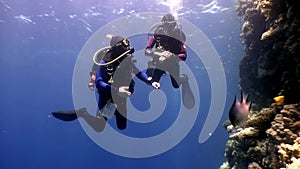 Two deepwater scuba divers swimming near coral reefs underwater in Red sea.