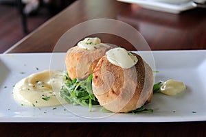 Two delicious crab cakes with lemon caper remoulade served over a bed of arugula photo