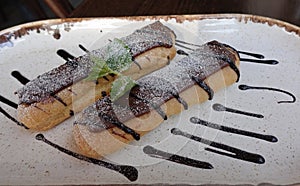 Two delicious eclairs on a plate drenched in chocolate