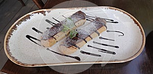 Two delicious eclairs on a plate drenched in chocolate