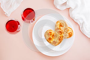 Two delicious heart-shaped pizzas on plates and two glasses of wine on a set table to celebrate valentine's day. Top view