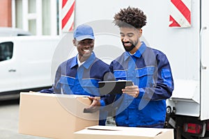 Two Delivery Men Looking At The Digital Tablet