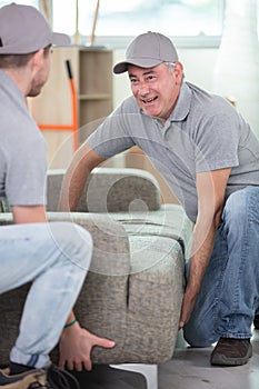 two delivery men in uniform unloading sofa