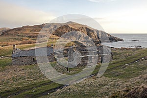 Two desolated stone houses at the shore