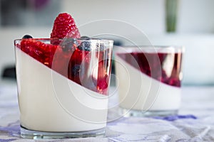 Two dessert glasses of panna cotta with strawberries, blueberries and berries