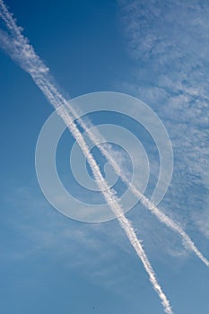 Two diagonal chem trails from airplanes in the blue sky photo