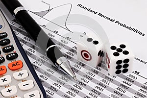 Two dice, calculator and pen on standard normal probabilities table.