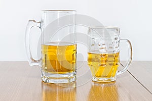 Two Different Beer Mugs Half Full with Lager