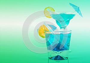 Two different blue cocktails with lemon and ice cubes, refreshing alcoholic drinks based on vodka and blue liqueur
