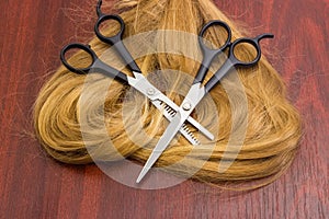 Two different hairdressers scissors on strand of hair on table