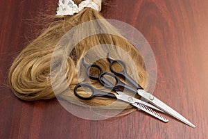 Two different hairdressers scissors on strand of hair on table